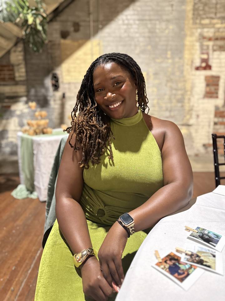 grace elizabeth oxley, creator of kindred and friendlove, smiling at a table with polaroids